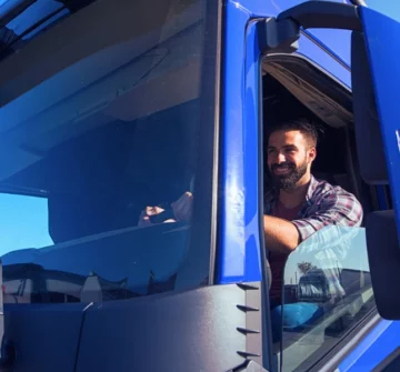 Happy truck driver driving a huge blue truck. commercial trucking laws