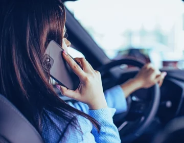 Woman using phone while driving in car. Distracted Drivers Cause Motorcycle Accidents