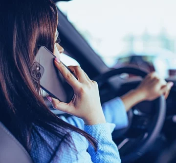 Woman using phone while driving in car. Distracted Drivers Cause Motorcycle Accidents