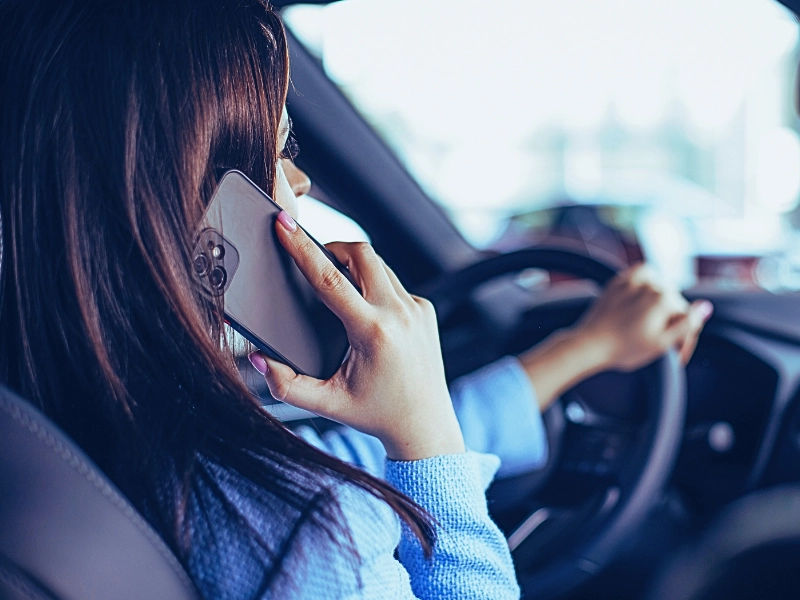 Woman using phone while driving in car. Distracted Drivers Cause Motorcycle Accidents