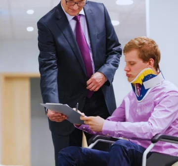 A man in a dark suit with a purple tie standing next to a person seated in a wheelchair. Ohio Comparative Negligence