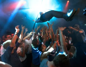 A crowd at a music event has their arms raised while tossing a person into the air. injured at a Cincinnati concert, injured at a festival, injured at a game