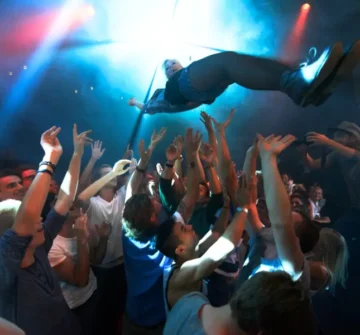A crowd at a music event has their arms raised while tossing a person into the air. injured at a Cincinnati concert, injured at a festival, injured at a game