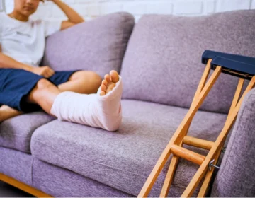 Person resting on couch with cast on leg and crutches. sue after an injury at an apartment complex