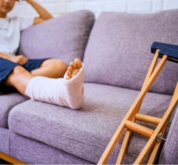 Person resting on couch with cast on leg and crutches. sue after an injury at an apartment complex