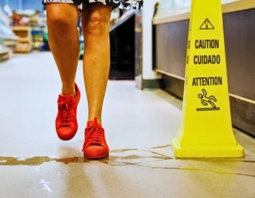 Person wearing red sneakers stepping near a yellow wet-floor sign. store owners responsible for customer injuries