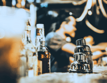 Some bottles of liquor on a bar counter and a bartender in the background. injury at a Cincinnati bar