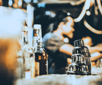 Some bottles of liquor on a bar counter and a bartender in the background. injury at a Cincinnati bar
